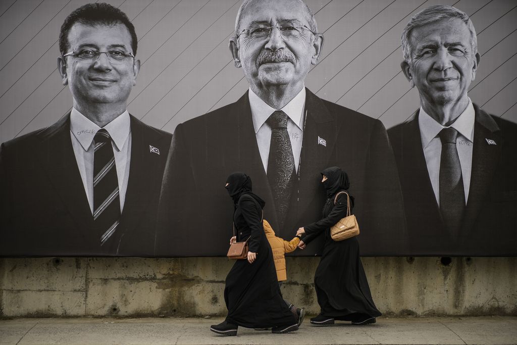 Dua oang perempuan berjalan di depan papan kampanye tiga tokoh partai oposisi, Partai CHP, di Istanbul, Turki, Sabtu (6/5/2023). Dalam dua jajak pendapat jelang pemilihan umum, tokoh oposisi Kemal Kilicdaroglu unggul atas petahana, Presiden Reccep Tayyip Erdogan. .