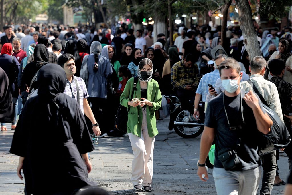 Seorang perempuan warga Iran berjalan di antara warga lainnya di tengah Grand Bazaar di Ibu Kota Iran, Teheran, Rabu (28/9/2022). Otoritas komunikasi Iran membatasi akses internet dari dan keluar negara itu agar informasi mengenai demonstrasi besar-besaran menyoal kematian Mahsa Amini tidak menggema. (Photo by ATTA KENARE / AFP)