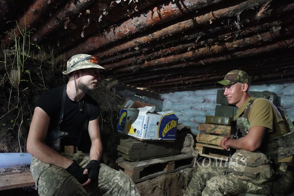 Dua tentara Ukraina berada di dalam parit di salah satu lokasi di sekitar garis depan pertempuran di wilayah timur Ukraina, Jumat (8/7/2022). Para prajurit menggunakan parit untuk berlindung dari serangan artileri.