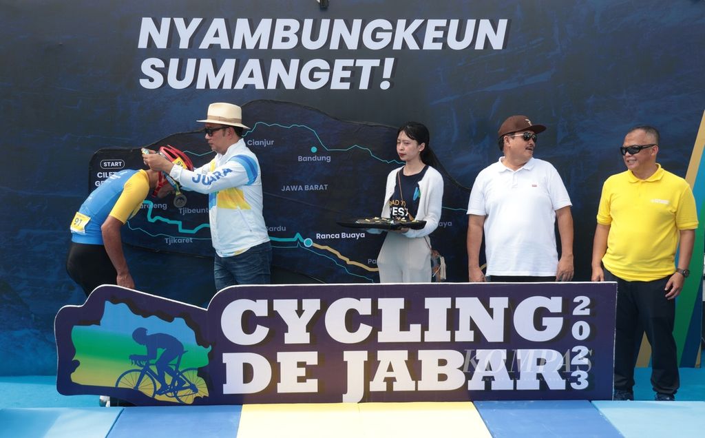 Gubernur Jawa Barat Ridwan Kamil (kedua dari kiri) didampingi Bupati Pangandaran Jeje Wiradinata (kedua dari kanan) dan Kepala Dinas Pemuda dan Olahraga Asep Sukmana (kanan) memberikan medali kepada <i>finisher</i> yang berhasil menyelesaikan etape kedua Cycling de Jabar 2023 di Pangandaran, Jawa Barat, Minggu (9/7/2023). 