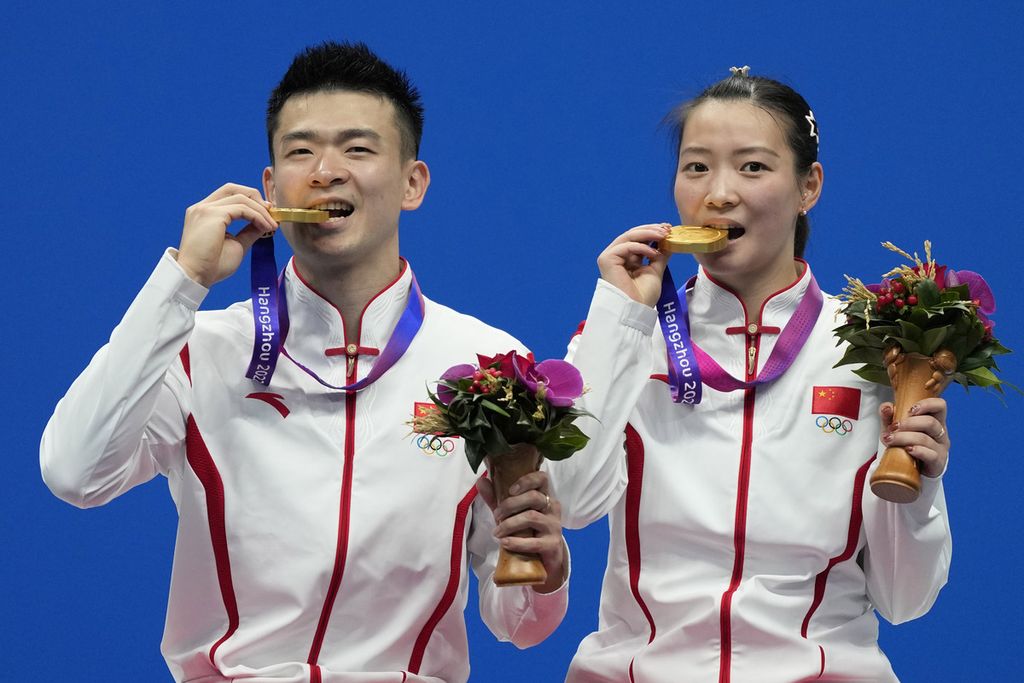 Peraih medali emas bulu tangkis ganda campuran Asian Games Hangzhou 2022, Zheng Ziwei (kiri) dan Huang Yaqiong, berpose dengan mengigit medali seusai upacara penyerahan medali di Binjiang Gymnasium Hangzhou, Sabtu (7/10/2023). 