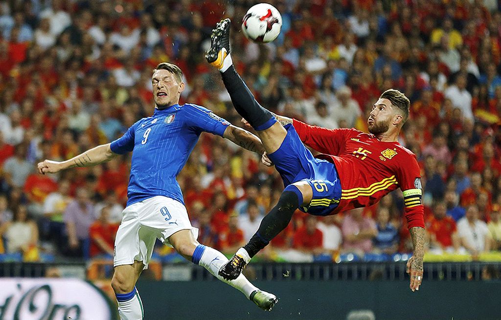 Bek tengah Spanyol, Sergio Ramos, berebut bola atas dengan striker Italia, Andrea Belotti, pada laga kualifikasi Grup G zona Eropa Piala Dunia 2018, di Stadion Santiago Bernabeu, Madrid, Sabtu (3/9) dini hari WIB. Spanyol tampil cemerlang dan menang telak 3-0.