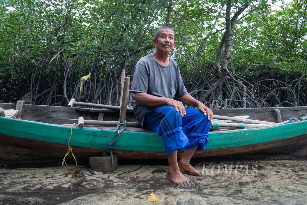 Seorang nelayan, Baharudin (65), menambatkan perahunya di antara pohon bakau di Kampung Tua Bakau Serip, Kota Batam, Kepulauan Riau, Sabtu (8/10/2022).