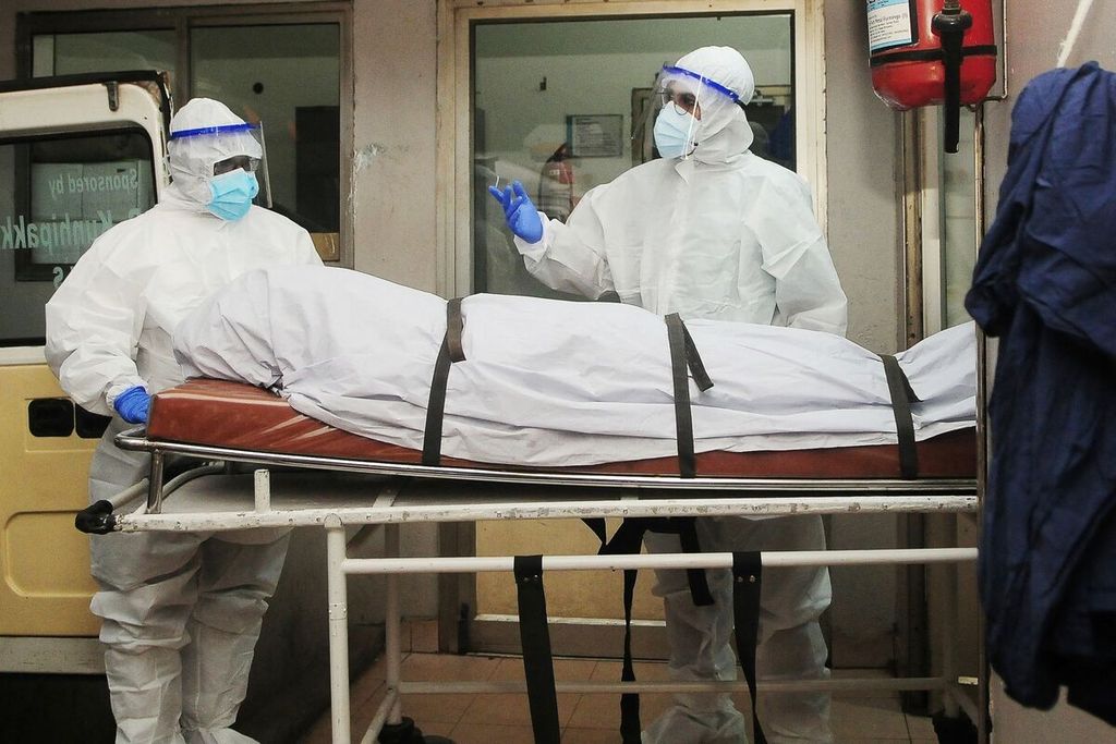 Petugas kesehatan, Selasa (12/9/2023), menggunakan alat pelindung diri atau <i>hazmat</i> saat membawa jenazah seorang terduga infeksi virus Nipah di sebuah rumah sakit di Kozikode,  Kerala, India.