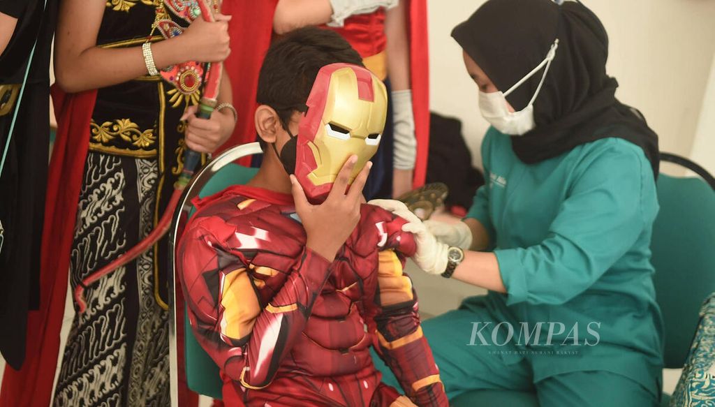 Siswa SD Pembangunan Jaya 2 berkostum superhero yang bertugas memberi semangat siswa ikut divaksin dosis kedua di Kabupaten Sidoarjo, Jawa Timur, Kamis (17/2/2022). Untuk memberi dukungan kepada kepada peserta vaksinasi, sejumlah siswa menggunakan kostum superhero. 