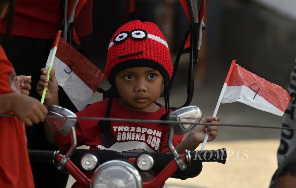 Seorang anak membawa bendera Merah Putih saat mengikuti perlombaan dalam rangka peringatan HUT Ke-78 RI di Jalan Lingkar Luar Barat, Cengkareng, Jakarta Barat, Kamis (17/8/2023). 