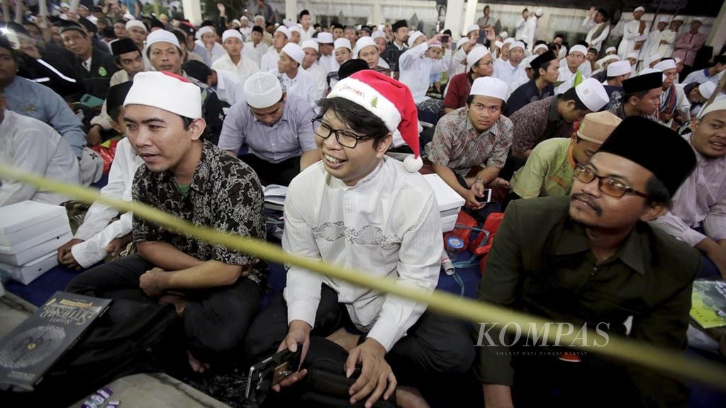 Alim (30) warga Tangerang datang mengunakan topi Santa pada Peringatan ke-7 Tahun wafatnya KH. Abdurrahman Wahid (Haul Gus Dur ) di kediaman Alm. Gus Dur di Ciganjur, Jakarta, Jumat (23/12/2016). Alim mengatakan bahwa ini bukan kali pertama, tapi telah tiga tahun terakhir ia selalu datang ke Haul Gus Dur mengunakan topi Santa sebagai simbol ungkapan toleransi.