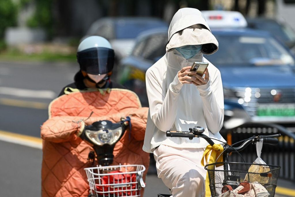 Warga menggunakan beragam pelindung untuk menghindari sengatan matahari saat berada di sebuah jalan di kota Shanghai pada Senin (29/5/2023). Pada hari itu dilaporkan, suhu udara di kota itu tercatat menjadi yang terpanas sepanjang Mei, atau hari terpanas dalam 100 tahun terakhir.