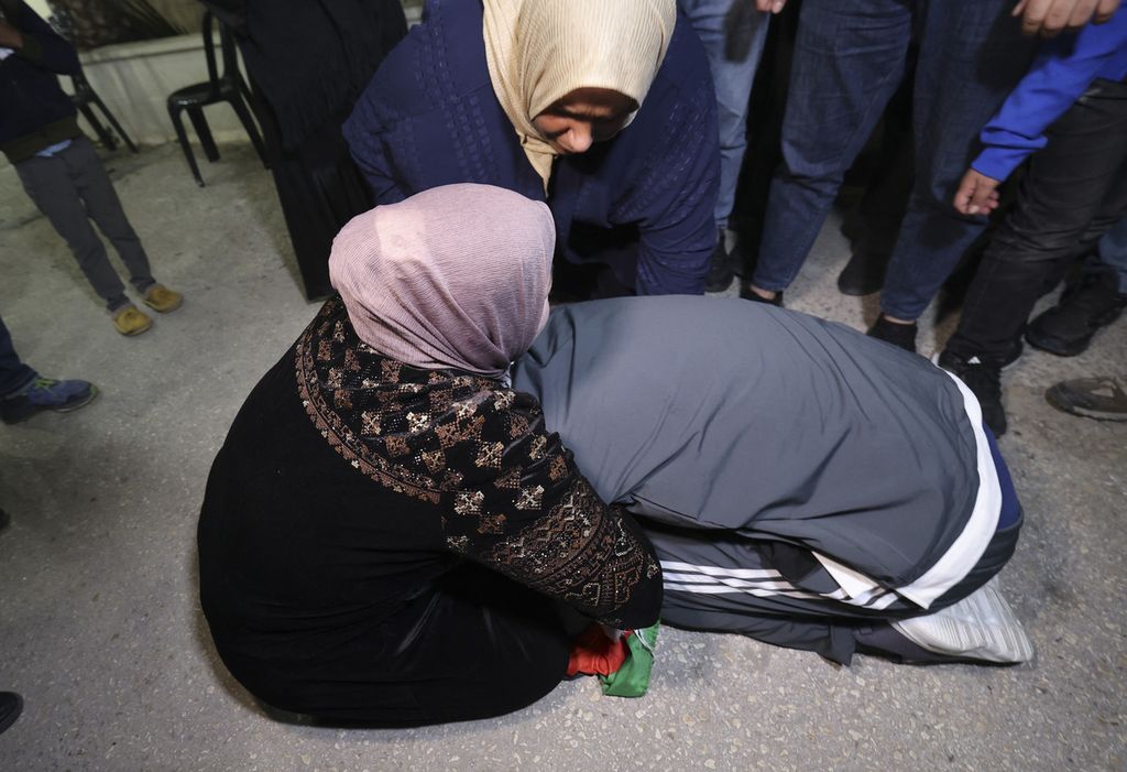 Khalil Zama’ (kanan) berlutut di depan ibunya setelah keduanya bertemu di rumahnya, di Desa Halhul, Hebron, Tepi Barat, Senin (27/11/2023). Dia dibebaskan dari penjara Israel setelah kelompok Hamas dan Israel sepakat melakukan jeda pertempuran empat hari dan bertukar tahanan, yang dimulai Jumat (24/11/2023). 