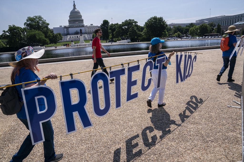 Peserta memegang tulisan Lindungi Anak-anak” saat unjuk rasa para ibu menuntut tindakan tegas atas kekerasan senjata, 8 Juni 2022, di Washington DC, Amerika Serikat. 