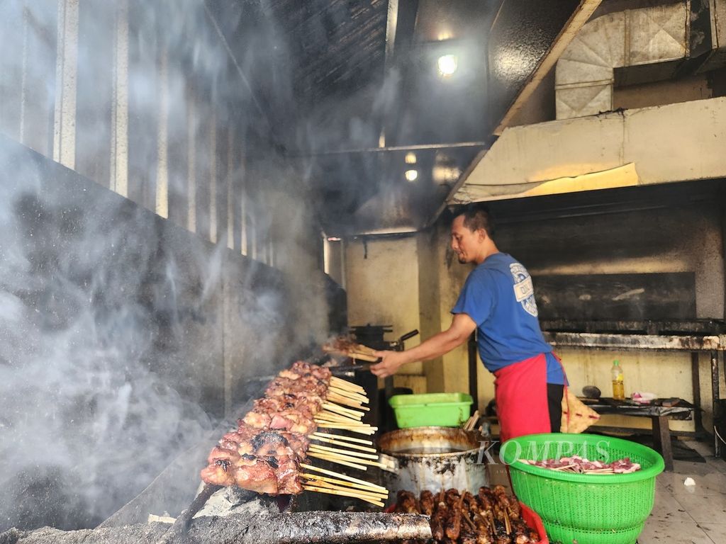 Juru masak membakar sate sebelum disajikan ke pelanggan di Warung Sate Kambing Pak Manto di Kota Surakarta, Jawa Tengah, Kamis (21/12/2023).