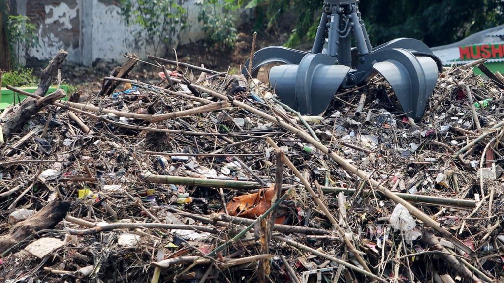 Petugas kebersihan mengeruk berbagai sampah, seperti batang tanaman, plastik, dan sampah rumah tangga, yang menumpuk di Pintu Air Manggarai, Jakarta, Selasa (8/1/2019). 