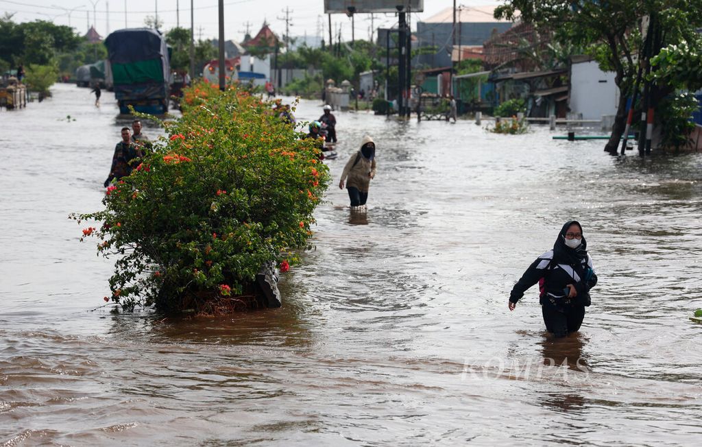 Warga melintasi genangan banjir yang masih terjadi di Kaligawe, Kota Semarang, Jawa Tengah, Senin (2/1/2023). Cuaca ekstrem di pengujung tahun 2022 menyebabkan terjadinya bencana banjir di banyak daerah di Pulau Jawa.