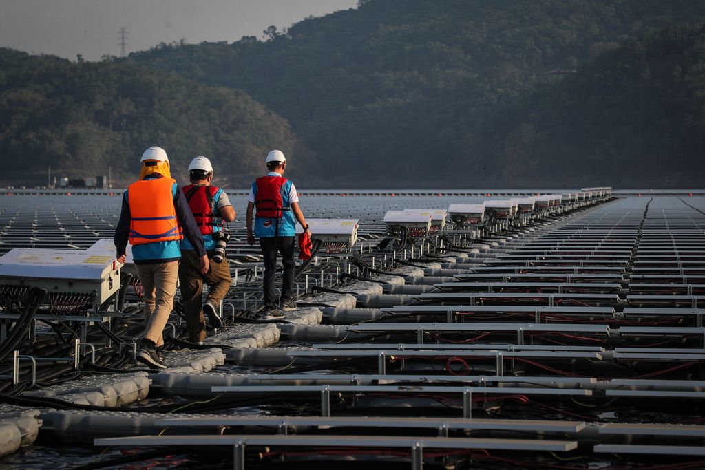 Pewarta foto berjalan di antara panel surya pada proyek PLTS Cirata di Purwakarta, Jawa Barat, Selasa (26/9/2023).