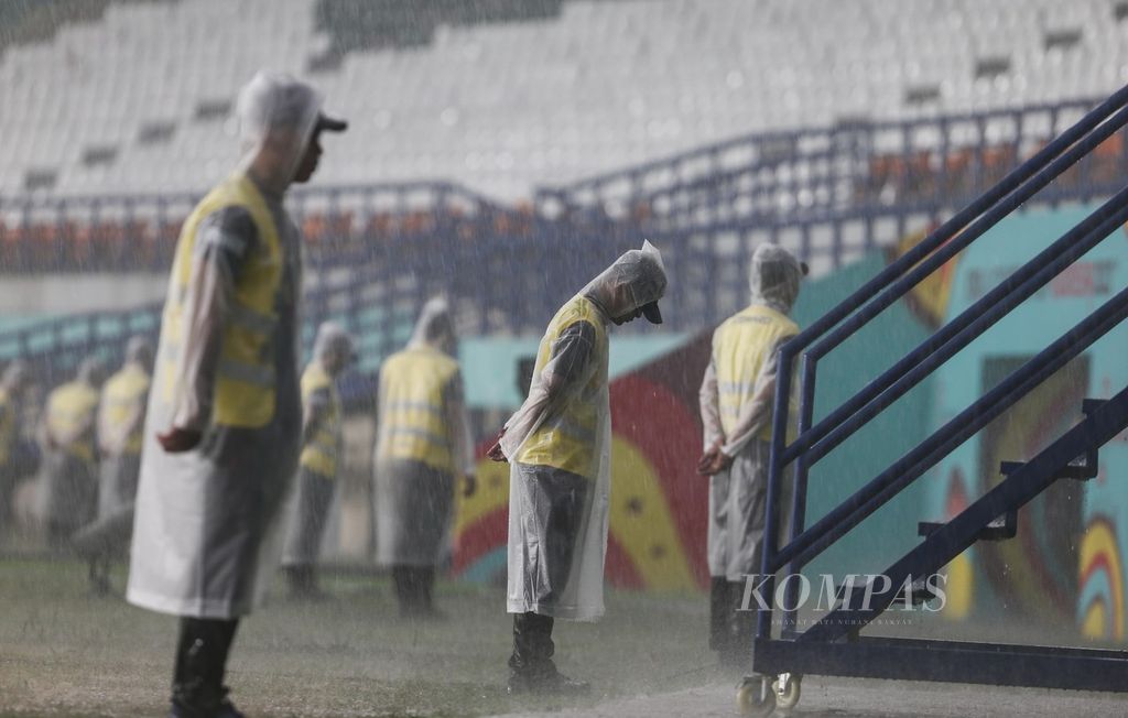Para petugas mengenakan jas hujan saat hujan deras mengguyur dalam laga penyisihan Grup D Piala Dunia U-17 2023 di Stadion Si Jalak Harupat, Kabupaten Bandung, jawa Barat, Sabtu (11/11/2023). 