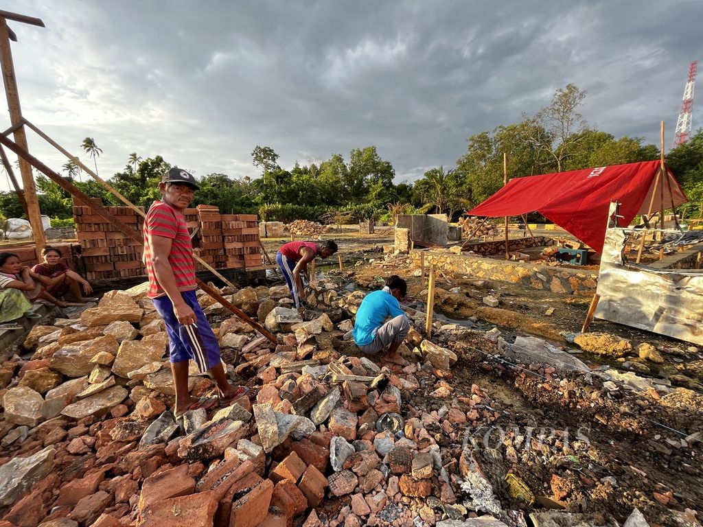 La Rudi (40), paling kiri, membangun fondasi rumahnya yang habis dilalap api, di Kelurahan Bungkutoko, Kendari, Sulawesi Tenggara, Senin (20/6/2022). Nelayan ini memang memiliki keahlian bangunan, yang menjadi sambilannya saat tangkapan berkurang. Perubahan iklim yang semakin nyata, membuat hasil melaut semakin kurang. Melaut selama sebulan, ayah tiga anak ini hanya bisa menghasilkan Rp 650.000.