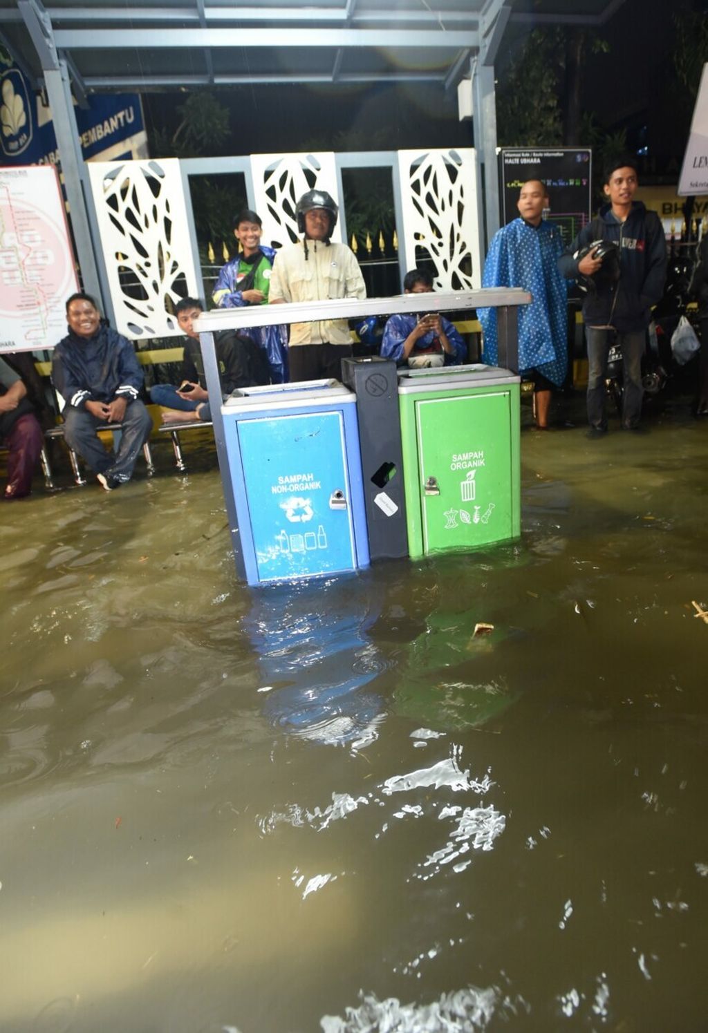 Pengendara yang menghindari banjir yang menggenangi Jalan Ahmad Yani menunggu banjir surut di halte bus, Surabaya, Jumat (31/1/2020). Hujan deras yang mengguyur dari pukul 15.30 hingga 19.00 di hampir seluruh wilayah Surabaya membuat sejumlah ruas utama jalan Kota Surabaya tergenang air dan menyebabkan kemacetan panjang. 