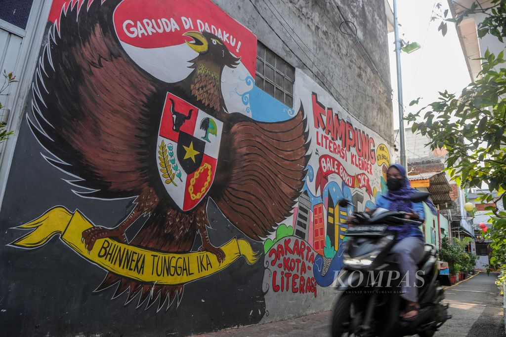 Warga mengendarai sepeda motor di samping mural Bhineka Tunggal Ika yang menghiasi RT 015 RW 004, Klender, Jakarta Timur, Senin (7/8/2023). 