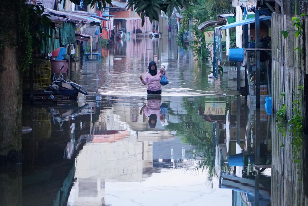 Warga Kelurahan Kemindung Permai, Kota Samarinda, Kaltim, berjalan melintasi banjir pada 11 Juni 2019.
