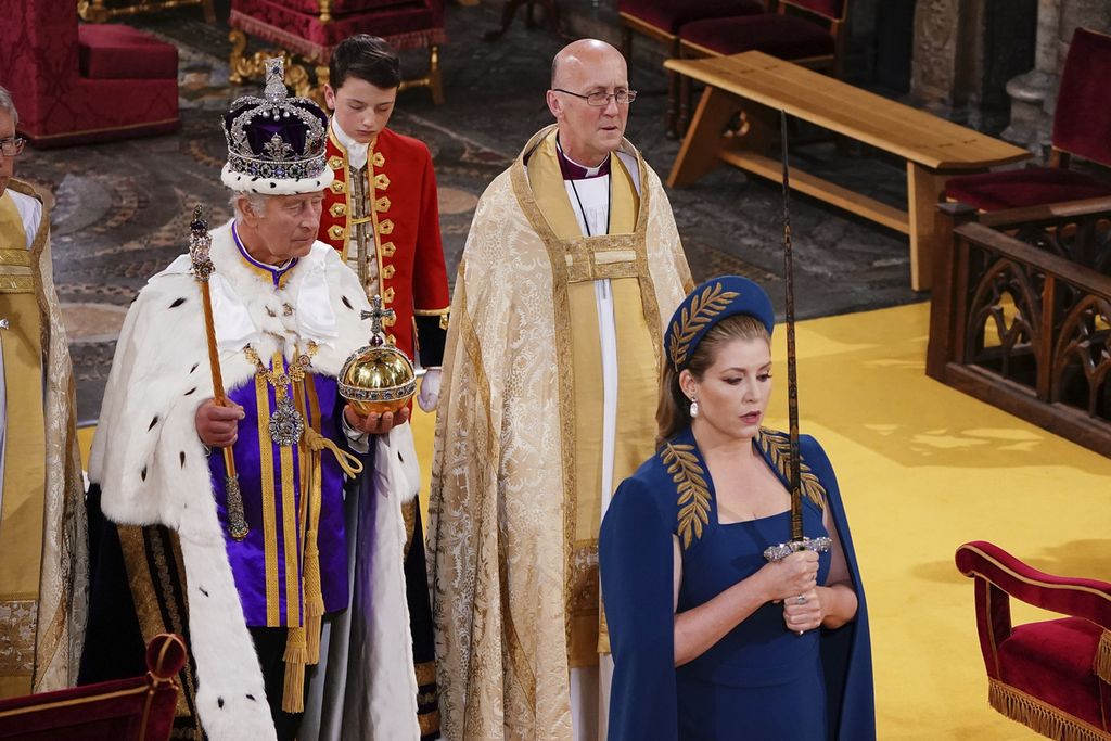Lord President of the Council, Penny Mordaunt (kanan), dengan memegang Pedang Kenegaraan, berjalan di depan Raja Inggris Charles III (kiri) dalam upacara penobatan Charles di Westminster Abbey, London, Sabtu (6/5/2023). 