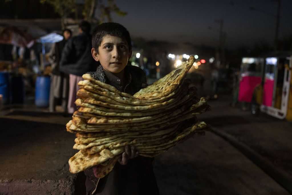 Seorang anak membawa tumpukan roti di Herat, Afghanistan, 25 November 2021. Organisasi Kesehatan Dunia (WHO) mengatakan, kelumpuhan ekonomi pascaperalihan kekuasaan bisa mengakibatkan jutaan anak Afghanistan terancam kelaparan. 