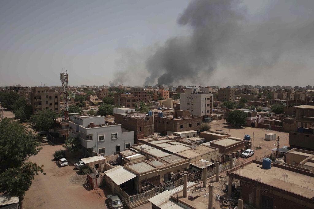 Asap hitam membubung dari pusat kota Khartoum, Sudan, Minggu (16/4/2023). Pertempuran sengit antara dua faksi militer telah menewaskan lebih dari 400 orang dan melukai ribuan orang. Ribuan warga kota Khartoum berusaha mengungsi keluar kota. (AP Photo/Marwan Ali)