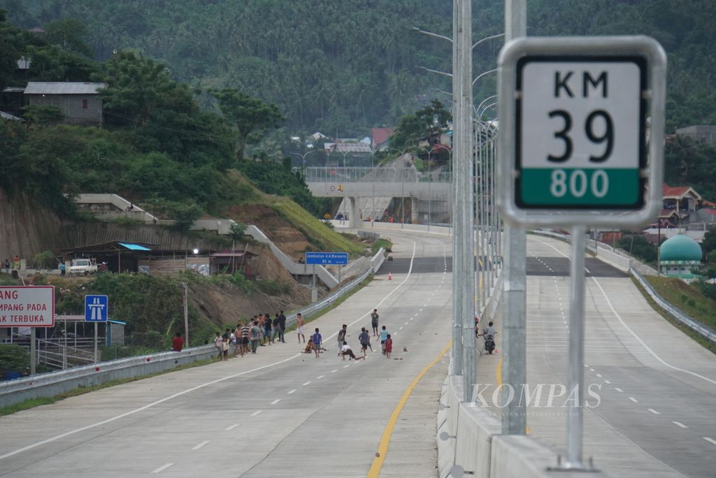 Anak-anak dan pemuda bermain di ujung timur Jalan Tol Manado-Bitung di Bitung, Sulawesi Utara, Jumat (21/1/2022). Mulai dibangun pada 2016, jalan tol sepanjang 39,8 kilometer itu akhirnya rampung dan siap digunakan.