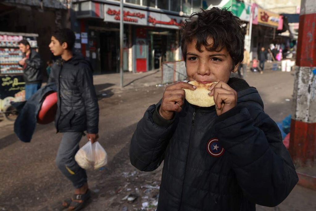 Seorang anak Palestina menggigit roti di Rafah, Jalur Gaza selatan, Senin (4/3/2024). Kantor Koordinasi Urusan Kemanusiaan PBB (UN OCHA) menyebutkan, sedikitnya 576.000 warga Gaza atau seperempat dari total populasi di enklave itu tinggal satu tahap masuk kategori kelaparan.