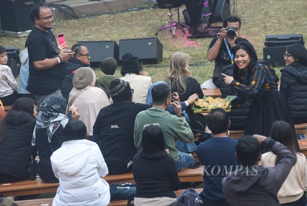 Louise Monique Sitanggang dari kelompok musik Deredia menawarkan makanan saat menyanyikan lagu berjudul Bala-bala dalam Jazz Gunung Bromo di Amfiteater Jiwa Jawa Resort, Kecamatan Sukapura, Kabupaten Probolinggo, Jatim, Jumat (21/7/2023). 