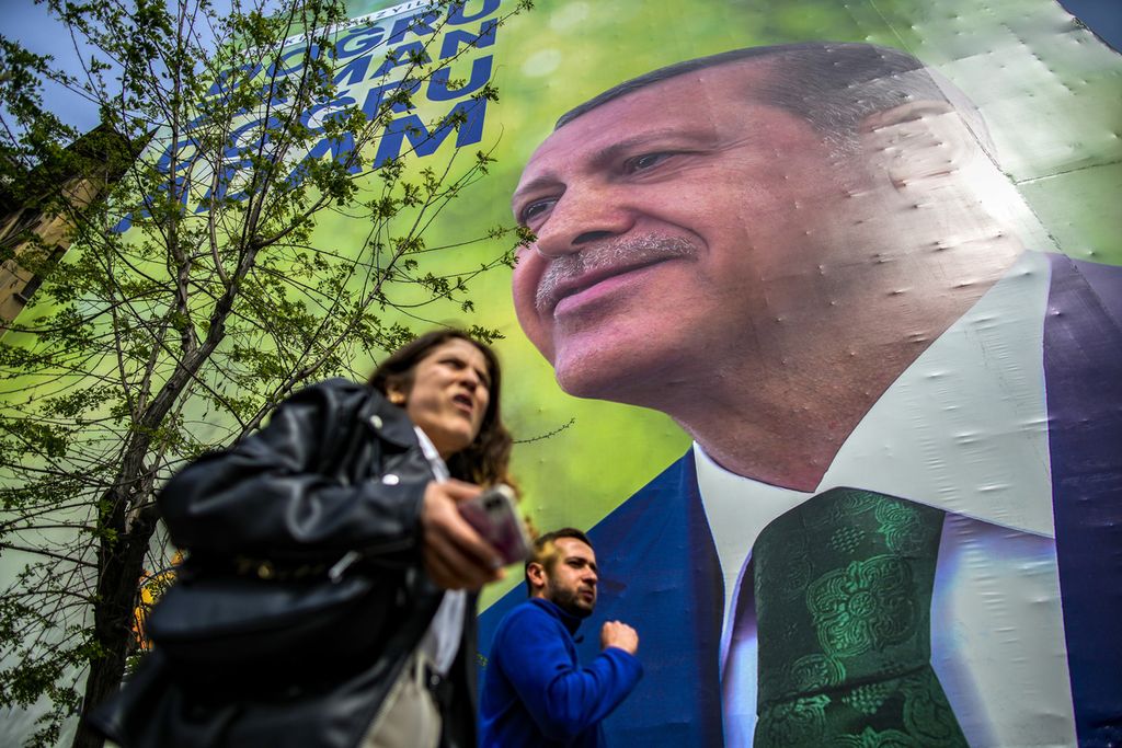 Warga berjalan kaki melintas di depan poster bergambar wajah Presiden Turki Recep Tayyip Erdogan di sebuah jalan di Istanbul, Turki pada Kamis (4/5/2023).