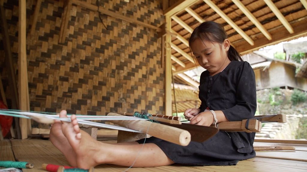 Mika (6) belajar menenun kain tenun ikat kepala di teras rumahnya di Kampung Marengo, Desa Kanekes, Lebak, Banten, Kamis (27/10/2022).