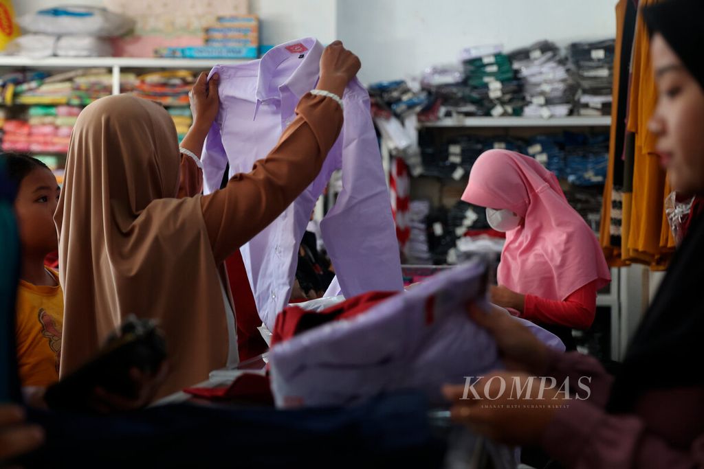 Salah satu orangtua yang memilih baju seragam untuk anaknya pada salah satu toko di Krapyak, Kota Semarang, Jawa Tengah, Jumat (14/7/2023).