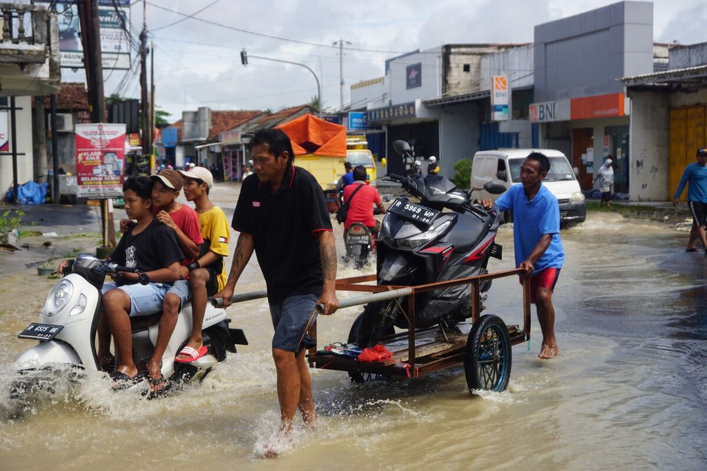 Warga melintasi banjir di Kawunganten, Cilacap, Jawa Tengah, Sabtu (8/10/2022). 