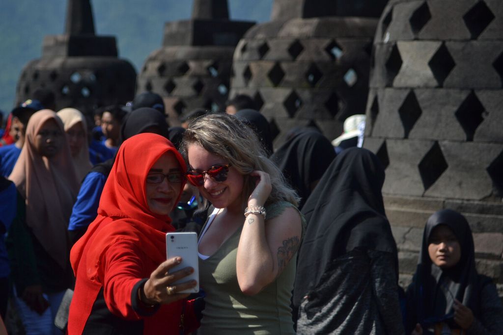 Wisatawan domestik berswafoto dengan wisatawan asing di lantai delapan Candi Borobudur, Magelang, Jawa Tengah, Kamis (13/2/2020). 