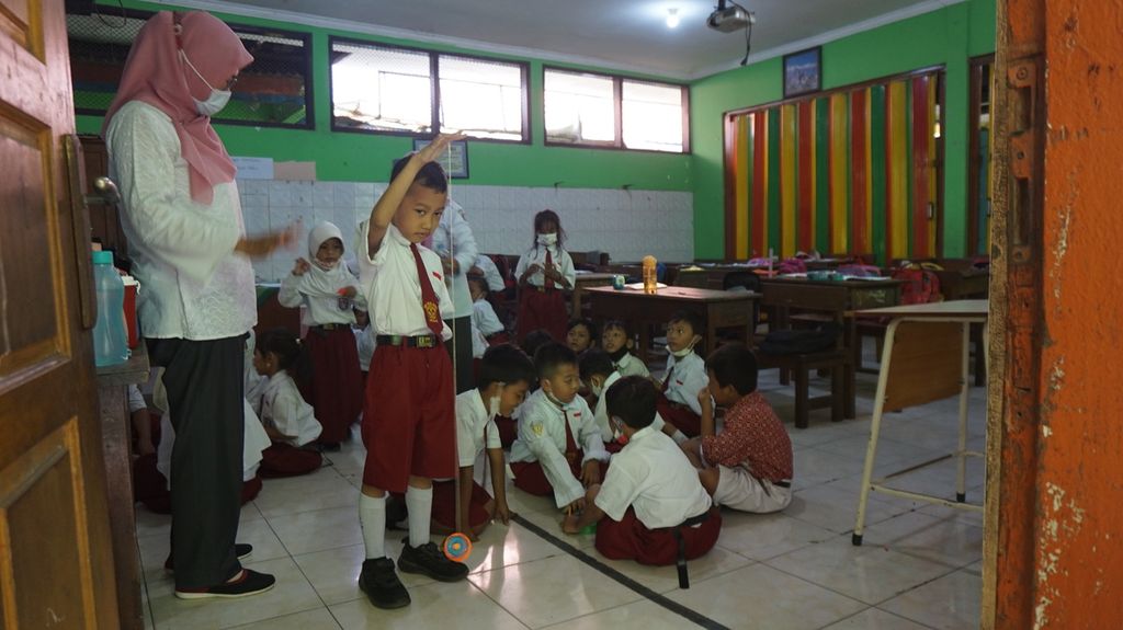 Guru memantau para murid kelas 1 SD Negeri Mojo 3, Surabaya, Jawa Timur, yang sedang mengisi waktu istirahat dengan permainan tradisional, Rabu (21/9/2022). 