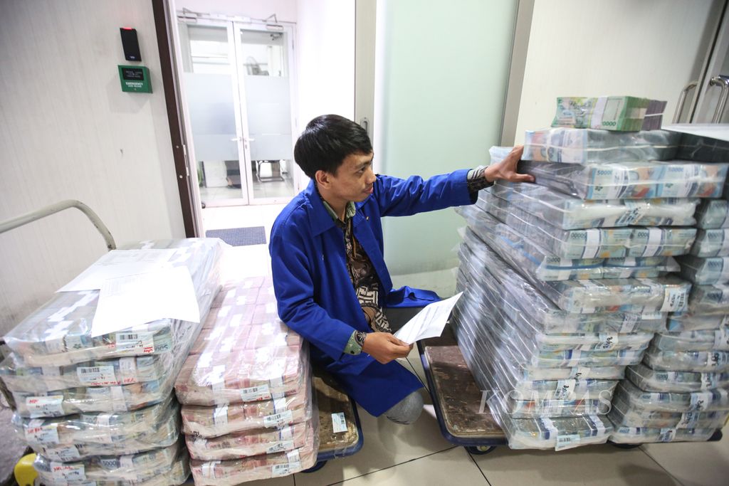 Petugas memeriksa tumpukan uang rupiah untuk dikirim ke kantor-kantor cabang dari Cash Pooling Bank Mandiri di Jakarta, Senin (11/12/2023).
