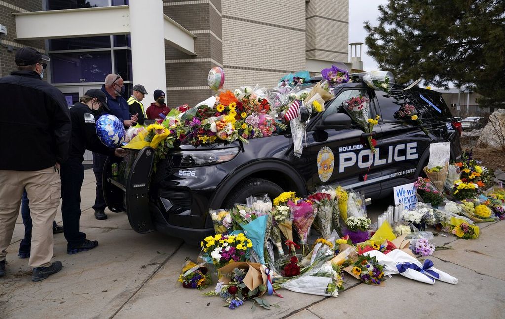Warga meninggalkan karangan bunga di mobil polisi yang berada di Kantor Kepolisian Boulder, Colorado, Amerika Serikat, Selasa (23/3/2021). Salah seorang polisi bernama Eric Talley (51) turut menjadi salah satu korban dalam penembakan massal di Supermarket King Soopers yang menewaskan 10 orang.