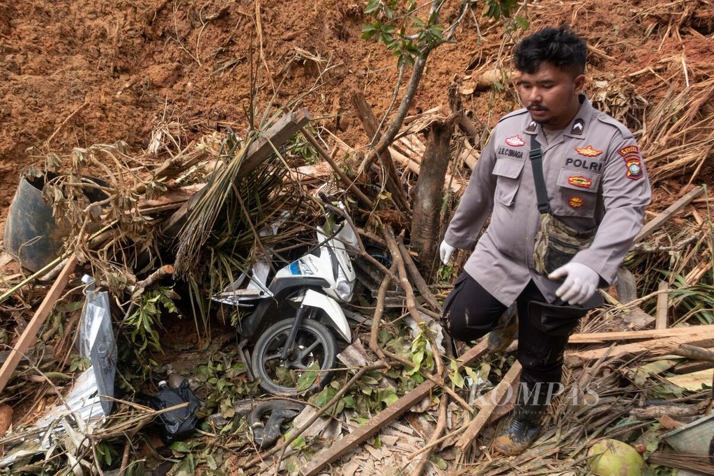 Seorang polisi anggota Satuan Tugas Tanggap Bencana Natuna membawa kantong jenazah untuk mengevakuasi korban bencana tanah longsor di Desa Pangkalan, Pulau Serasan, Natuna, Kepulauan Riau, Sabtu (11/3/2023).