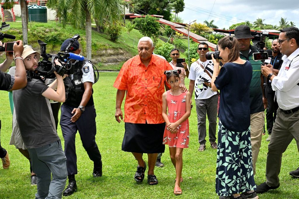 Perdana Menteri Fiji Frank Bainimarama bersama cucu perempuannya datang ke tempat pemungutan suara di Sekolah Yat Sen di ibu kota Suva, Fiji, Rabu (14/12/2022). Bainimarama untuk ketiga kalinya mencalonkan diri sebagai PM.