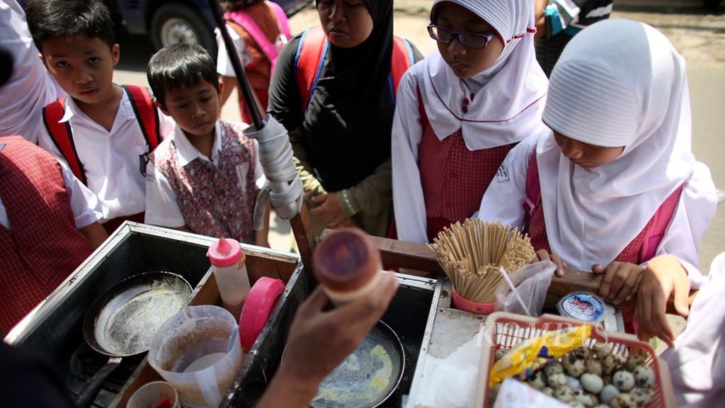 Para pelajar sekolah dasar di Tanah Abang, Jakarta, membeli jajan dari pedagang kaki lima, Selasa (26/1/2016). Kebersihan jajanan menjadi penting karena bisa menjadi sarana penyebaran adenovirus yang menyebabkan gangguan kesehatan, mulai dari saluran pernapasan, pencernaan, hingga hepatitis.