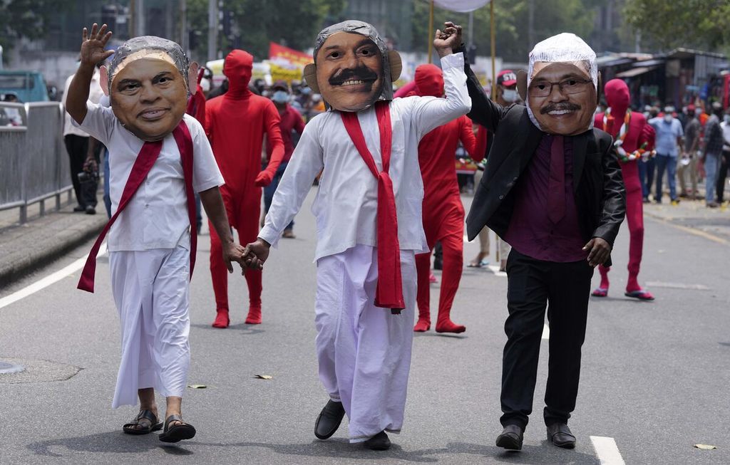 Sebanyak tiga anggota Persatuan Pemuda Sosialis memakai topeng dalam unjuk rasa di Colombo, Sri Lanka, 18 Maret 2022. Setiap topeng merujuk pada Presiden Sri Lanka Gotabaya Rajapaksa (kanan), Menteri Keuangan Basil Rajapaksa (kiri), dan Perdana Menteri Mahinda Rajapaksa (tengah).