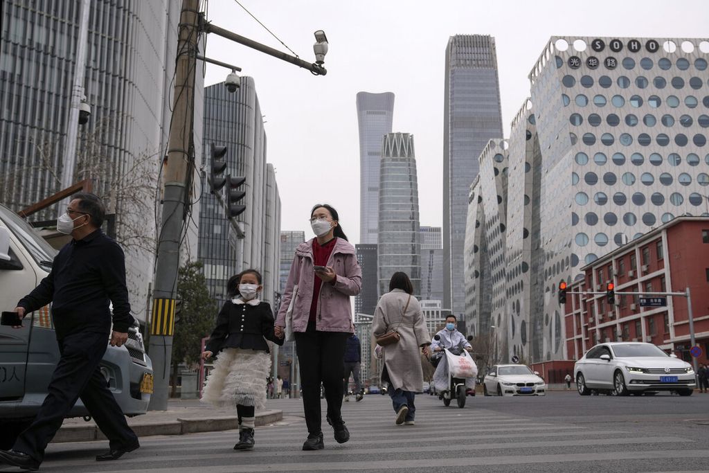 Pejalan kaki dan pengendara melintasi kawasan bisnis di Beijing, Sabtu (11/3/2023). China menunjuk Li Qiang sebagai perdana menteri negara berikutnya untuk menghadapi tantangan ekonomi dan politik China di kawasan global. 