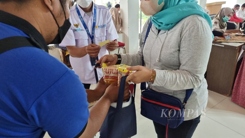 Seorang warga menerima paket minyak goreng dari petugas saat operasi pasar di Kantor Kecamatan Gedebage, Kota Bandung, Jawa Barat, Senin (7/3/2022). Operasi pasar ini diadakan Dinas Perdagangan dan Perindustrian Kota Bandung dan Perum Bulog Kantor Cabang Bandung