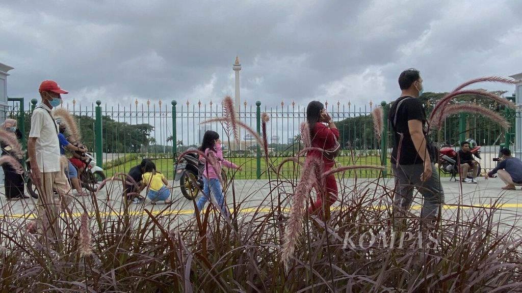 Warga meninggalkan kawasan Monas setelah berfoto dari balik pagar Tugu Monas Jakarta, Minggu (14/2/2021). Meski masih ditutup untuk umum sejak awal pandemi Covid-19, kawasan Monas tetap banyak dikunjungi warga untuk mengisi masa liburan. 