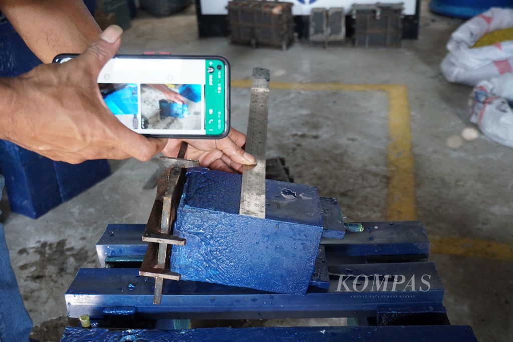 Jemsi Indra Yandi, staf operasional Baciraro Recycle, mengukur batako plastik yang dicetak dari mesin ekstruder di studio daur ulang Baciraro Recycle di Minahasa, Sulawesi Utara, Kamis (9/6/2022).