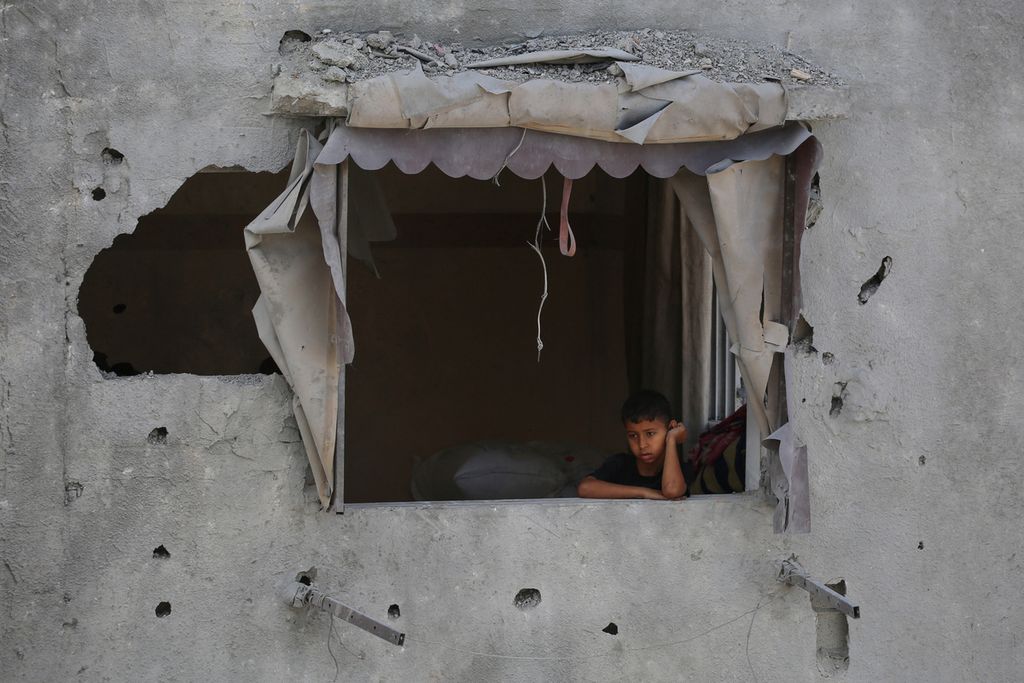 Seorang anak laki-laki Palestina melihat kehancuran dari jendela sebuah rumah yang rusak setelah pengeboman Israel di Distrik Tal al-Sultan Rafah di Jalur Gaza selatan, Selasa (7/5/2024). 