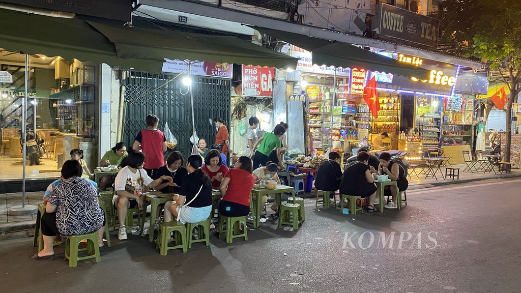 Warga duduk di kursi pendek di pinggir jalan untuk menikmati pho di kawasan Old Quarter, Hanoi, Vietnam Sabtu, (14/5/2022). Pho merupakan olahan mi beras dengan potongan daging ayam atau sapi dan kuah kaldu ayam atau sapi.