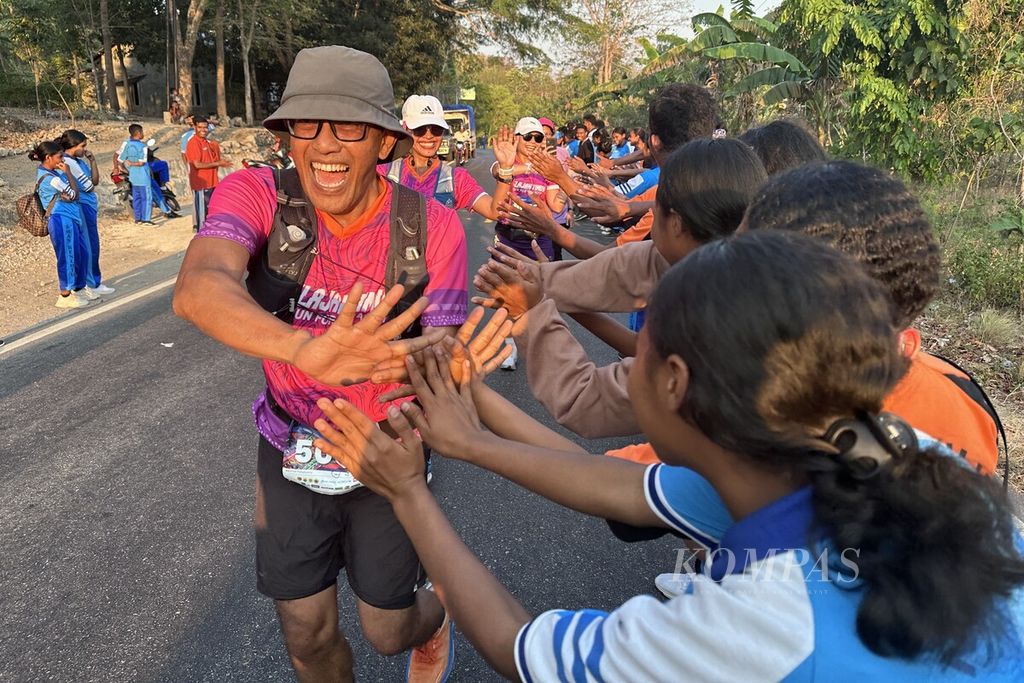 Para siswa Sekolah Menengah Atas Negeri Benlutu, Kecamatan Batu Putih, Kabupaten Timor Tengah Selatan, Nusa Tenggara Timur, menyalami dan memberi semangat para pelari Jelajah Timur 2023 yang melintas di hadapan mereka, Jumat (27/10/2023) sore. 