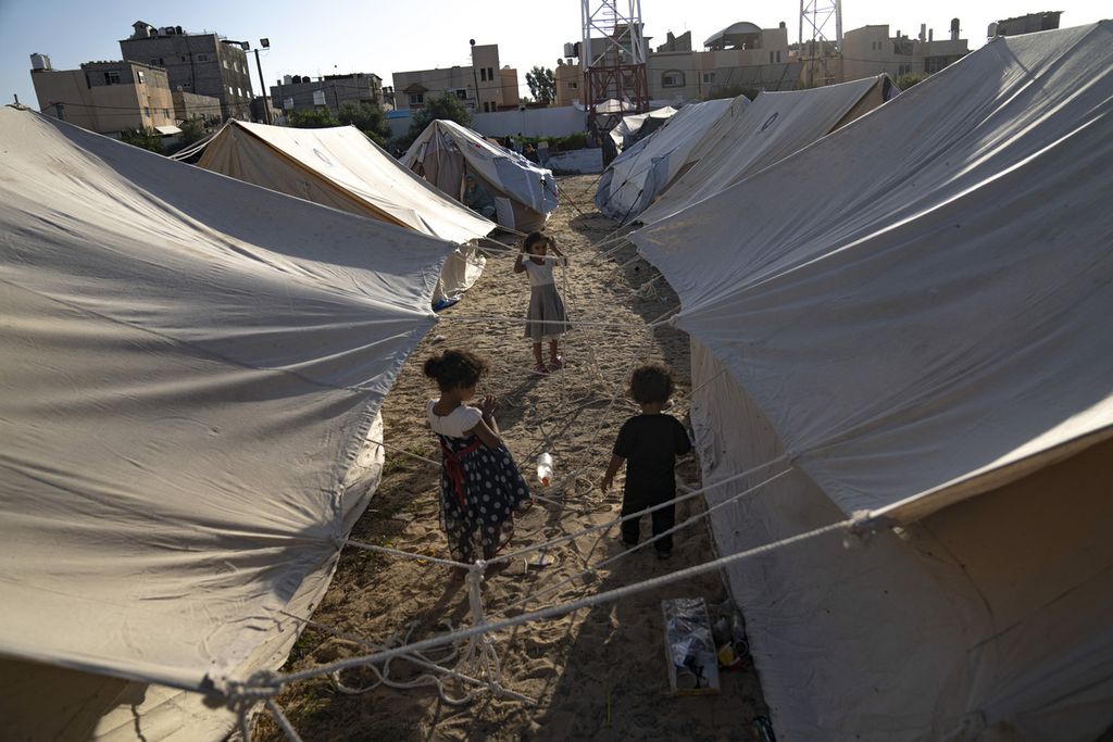Anak-anak Palestina yang mengungsi akibat pengeboman Israel di Jalur Gaza berjalan di antara tenda di kamp pengungsian yang disediakan UNDP di Khan Younis, Kamis (19/10/2023). 