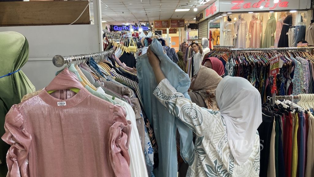 Sejumlah pembeli melihat gamis berbahan <i>shimmer</i> yang dijual di pusat perbelanjaan Thamrin City, Jakarta, Senin (8/4/2024) siang. Busana itu dijual dari harga Rp 200.000-an hingga Rp 500.000 atau lebih.